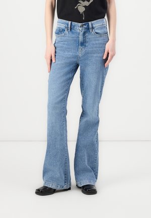 Light blue denim flared jeans feature a high waist, five-pocket design, and visible stitching, paired with a black graphic t-shirt.