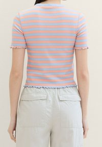 Top de manga corta acanalado con rayas horizontales en rosa y azul, presenta un escote y un dobladillo con volantes, combinado con pantalones cargo beige claro.