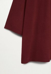 Bordeauxfarbener Pullover mit strukturierter Ripp-Optik, breiten Ärmeln und geradem Saum. Weiches Strickmaterial mit glatter Oberfläche.