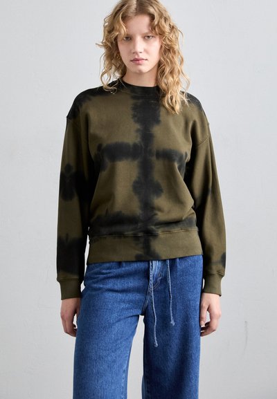 Hanorac tie-dye verde măslinie cu accente negre, guler rotund și manșete cu nervuri. Purtați cu blugi albaștri din denim cu șnur.