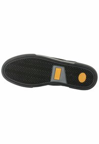Black rubber shoe sole with a herringbone pattern, featuring a textured section and a yellow circular accent near the heel.