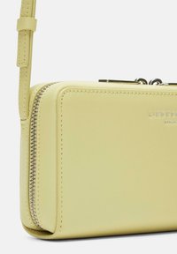 Żółta skórzana torebka na ramię z zamkiem błyskawicznym, z widocznym ściegowaniem i gładką teksturą, oznakowana wytłoczonym detalem.