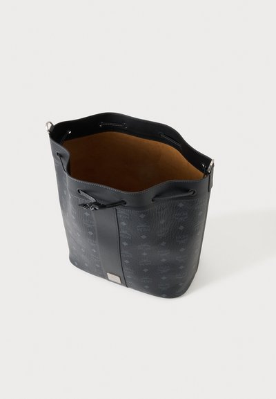 Sac seau en cuir noir avec un motif subtil, fermeture par lien coulissant et intérieur fauve, présenté en vue plongeante inclinée.