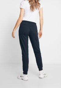 Marine joggerpants met een taps toelopend ontwerp, elastische tailleband en zijzakken. Gecombineerd met een wit t-shirt en witte sneakers.