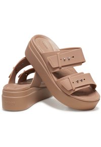 Sandales à plateforme Crocs beige avec brides à boucle réglable et semelle intérieure texturée, arborant le logo Crocs sur les brides et le talon.
