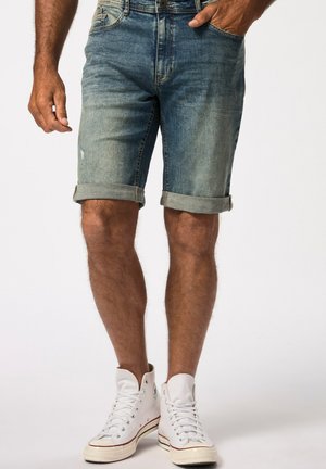 Shorts en denim bleu clair avec des zones décolorées et des ourlets retroussés, associés à des baskets montantes blanches. Design traditionnel à cinq poches.