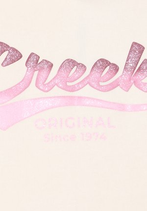Tessuto color crema con un testo lucido e sfumato in rosa, con la scritta "Creek" e "Originale dal 1974" in finitura glitter.