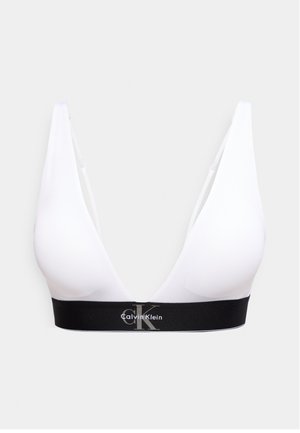Sutien tip braletă alb, cu cupă moale și decolteu adânc în V, cu bandă elastică neagră pe care este imprimat logo-ul Calvin Klein în alb și gri.