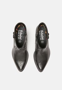 Botas de tobillo de cuero negro con puntas afiladas, que cuentan con costuras decorativas, una cremallera lateral y un forro interior de patrones multicolores.