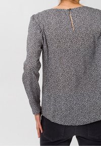 Blus med långa ärmar, svartvitt djurmönster, texturerad tyg, rundad kant, nyckelhålsdetalj i ryggen och avslappnad passform.