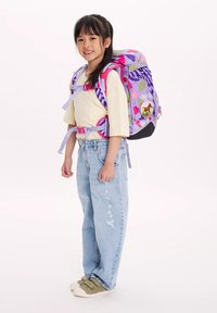 Zaino floreale viola e rosa con spalline regolabili e una toppa rotonda a forma di cavallo, indossato da un bambino con una maglietta gialla chiara e jeans larghi.