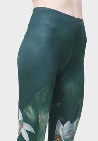 Hoch geschnittene Leggings in dunklem Gr�ün mit strukturierter Oberfläche. Sie verfügen über ein florales Muster mit weißen Blumen und grünen Blättern, das ein lebendiges Design bietet.