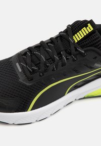 Baskets de sport noires avec tige en mesh, accents réfléchissants et bande verte fluo. Dotées d'un embout renforcé et d'une semelle texturée pour une meilleure adhérence.