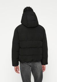 Černá péřová bunda s kapucí, která má polstrovaný design, rovný střih, elastické manžety a hladký povrch.