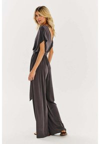 Sivý overal vo voľnom strihu, s krátkymi rukávmi, hlbokým V- výstrihom na chrbte a sťahovacím pásom. Vyrobený z ľahkej, hladkej tkaniny.