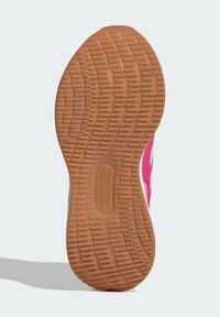 Semelle de chaussure en caoutchouc texturé. Présente un design de semelle à motifs et une tige en mesh rose et gris.