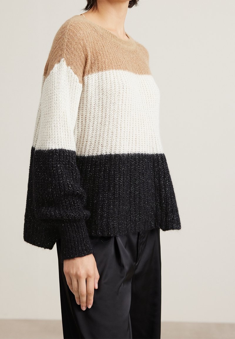 Pull en tricot épais avec un design en blocs de trois couleurs : marron, blanc et noir. Texture côtelée avec de larges manches et un col rond.