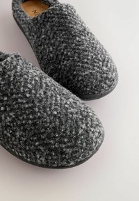 Grå f�ølte hjemmesko med en textured overflade og rund tådesign, der har en mørk gummisål og neutral indvendig foring.