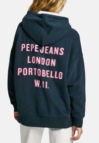 Felpa blu navy con testo rosa che recita "PEPE JEANS LONDON PORTOBELLO W.11." Tessuto morbido, vestibilità oversize, cappuccio con cordoncino.