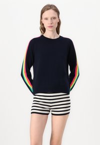 Navy pullover sweater with colorful rainbow stripes on sleeves, paired with black and white striped shorts. Soft knit material and cropped design.