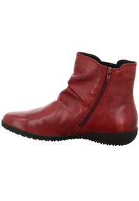 Botte chevillère en cuir rouge avec un design flasque, fermeture éclair sur le côté, bout arrondi et semelle en caoutchouc noir avec des motifs de traction texturés.