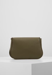 Borsa a spalla in pelle verde oliva con una texture liscia, forma arrotondata e cuciture decorative lungo i bordi. Design minimalista.
