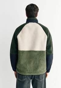 Fleece pullover med høj krave; har mørkegrønne, lyse beige og marineblå paneler; tekstureret, blødt materiale; afslappet pasform.