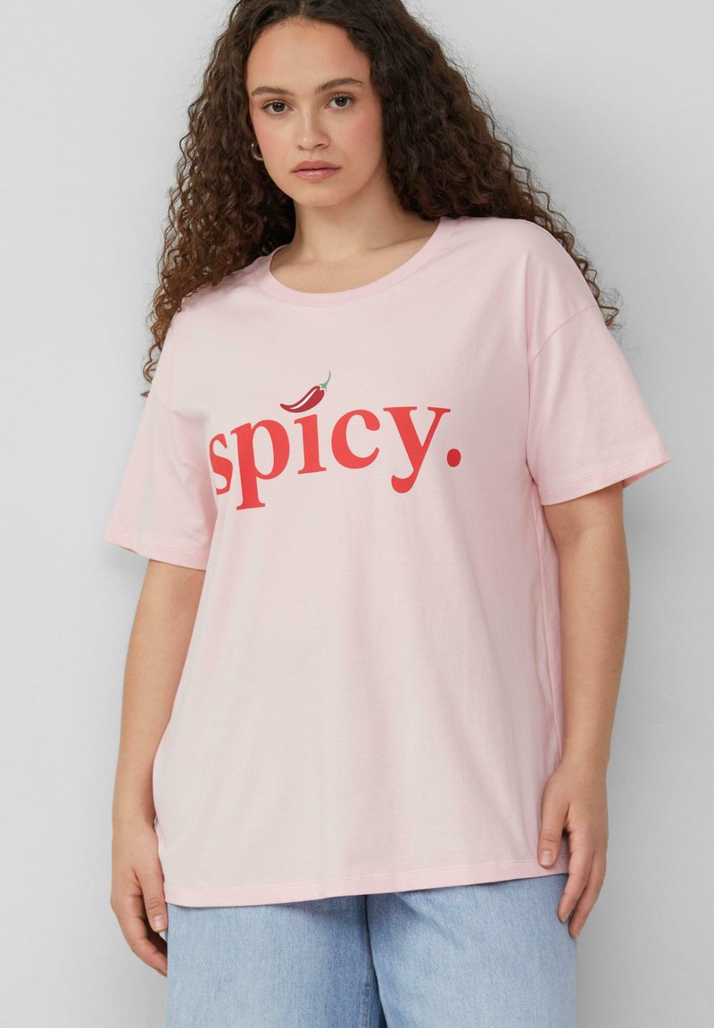 Lichtroze katoenen t-shirt met een rode opdruk die "spicy." zegt, met een kleine chilipeperaccent boven de tekst. Korte mouwen en een relaxte pasvorm.