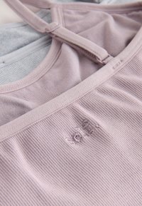 Reggiseno sportivo color malva chiaro con trama a coste, spalline regolabili e logo ricamato discreto. Tessuto morbido, design minimalista.