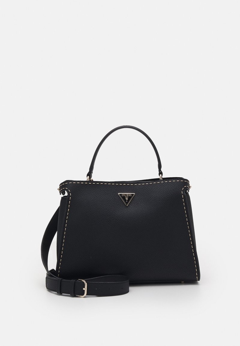 Sac à main en cuir noir avec poignée courte, bandoulière réglable, coutures blanches et petit logo triangulaire Guess à l'avant.