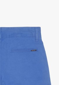 Pantaloni in cotone blu con tasca posteriore dotata di etichetta "HACKETT" in bianco e nero, rifiniti con cuciture pulite.