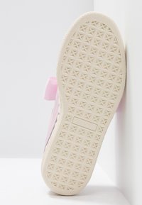 Rosa Sneaker mit einer strukturierten Gummisohle, die ein Sternmuster aufweist. Mit einer weichen rosa Schleifenakzent und einem Markenlogo an der Seite.