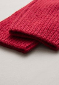 Écharpe en laine tricotée côtelée rouge pliée, mettant en valeur une texture douce et un motif régulier. Les bords sont nets, sans éléments métalliques ni accents visibles.