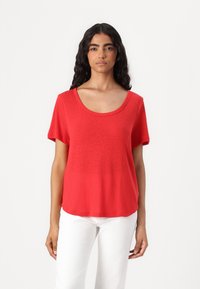 T-shirt rosso a maniche corte con scollatura a barca, realizzato in un tessuto leggero e morbido. Ha una vestibilità comoda e una texture liscia.