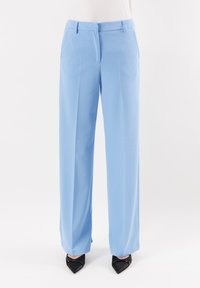 Pantaloni a gamba larga blu chiaro con una consistenza liscia, dotati di tasche frontali e vita piatta. Abbinati a tacchi a punta neri.