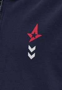 Marintröja i fleece med en röd stjärna och tre vita chevronmönster tryckta på framsidan, med en jämn yta och dragkedjestängning.