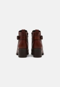 Hnědé kožené kotníkové boty s hladkým povrchem, se dvěma ozdobnými přezkami, zadním zipem a robustním podpatkem.