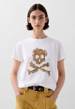 Witte katoenen T-shirt met een gestructureerd leopardenprint schedel-en-kruisbones ontwerp, met herhaalde tekstelementen in het zwart. Met een ceintuur in de taille.