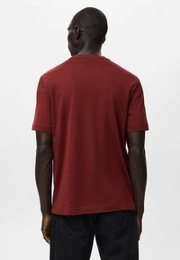 Bordowa bawełniana koszulka z krótkimi rękawami, okrągłym dekoltem i gładką fakturą. Prosty design, bez wzorów ani akcentów. Widok od tyłu.