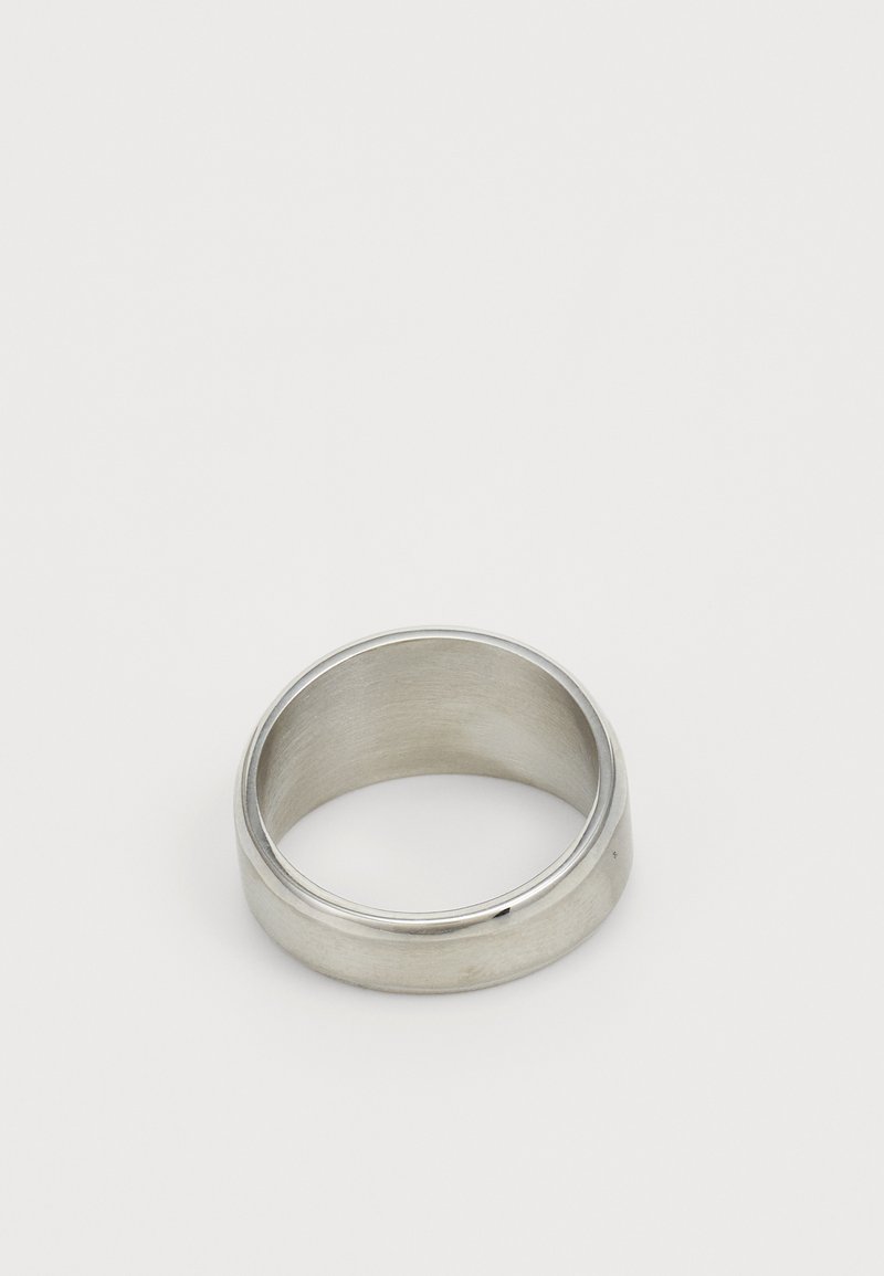 Bague en métal argenté avec une finition lisse et mate et un extérieur légèrement arrondi. L'intérieur présente un détail de rainure subtil.