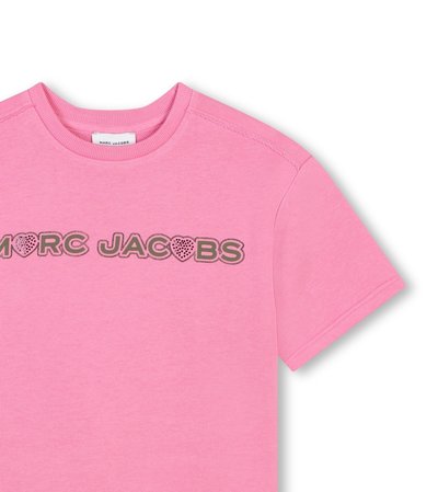 T-shirt en coton rose à manches courtes, avec le texte "MARC JACOBS" en lettres grasses et soulignées, agrémenté de cœurs. Encolure ronde, coupe décontractée.