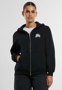Felpa nera con zip, realizzata in materiale morbido, con un design di rosa ricamato sul lato sinistro del petto e tasche frontali.