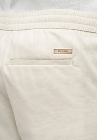 Μπεζ φόρμα με ελαστική μέση και μικρό λογότυπο Calvin Klein πάνω από μια πίσω τσέπη με σχισμή.