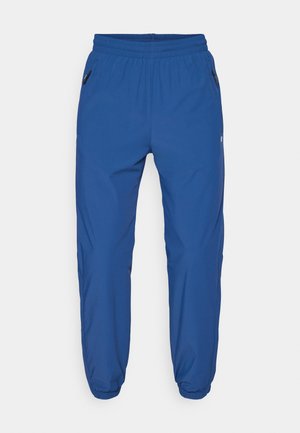 Blå atletiske bukser lavet af glat stof, med elastisk talje, sidelommer med lynlås og tapered ben med elastiske manchetter.