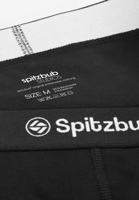 Zwart stretchstof kledingstuk met een witte merkrand en wasvoorschriftenlabel. Samenstelling: 95% katoen, 5% elastaan. Maat: M.