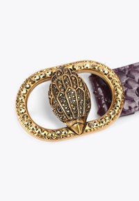 Złota klamra paska z teksturowanym wzorem sowy, ozdobiona czarnymi i przezroczystymi kamieniami szlachetnymi, przymocowana do fioletowego teksturowanego paska.