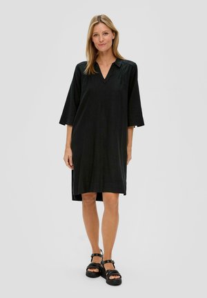 Schwarzes knielanges Kleid mit V-Ausschnitt, dreiviertel Ärmeln und seitlichen Schlitzen. Hergestellt aus einem weichen Material mit glatter Textur.