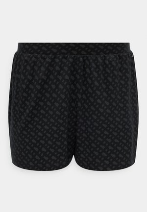 Mustad sportlikud lühikesed püksid, millel on peen tumedate geomeetriliste mustritega ja elastne taljeäär, eksponeeritud lihtsal valgel taustal.