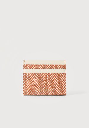 Suport pentru carduri texturat maro și alb cu două sloturi crem pentru carduri și logo auriu "Coccinelle" în partea de jos, în centru.