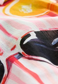 Multikleurige stof met gedurfde patronen in roze, oranje en zwart. De textuur lijkt licht en iets doorschijnend te zijn.